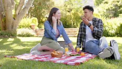 Happy-diverse-couple-having-picnic-in-sunny-garden,-copy-space,-in-slow-motion