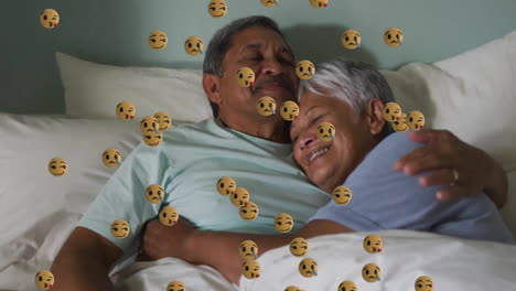 Animation-Von-Emoji-Symbolen-über-Einem-älteren,-Gemischtrassigen-Paar,-Das-Sich-Im-Bett-Umarmt
