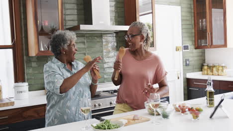 Glückliche-ältere-Afroamerikanische-Freundinnen,-Die-Essen-Zubereiten-Und-In-Der-Küche-Singen,-Zeitlupe