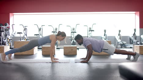 Fitte-Junge-Kaukasische-Frau-Und-Afroamerikanischer-Mann-Führen-Im-Fitnessstudio-Planks-Durch