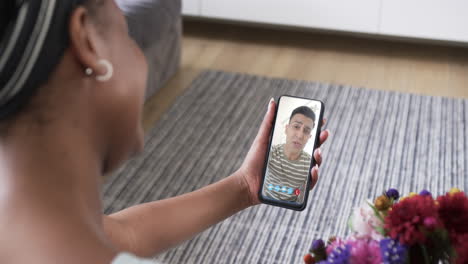 Biracial-woman-holding-smartphone-with-biracial-man-with-envelope-on-screen