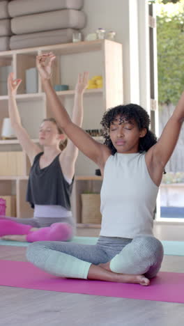 Vertical-video-of-diverse-women-exercising-on-mats-and-meditating,-slow-motion