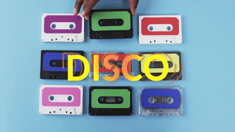 Animation-of-yellow-disco-text-over-hand-of-african-american-woman-holding-tape-on-blue-background