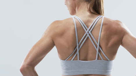 Close-up-of-a-young-Caucasian-woman-athlete's-back,-showcasing-sportswear-on-a-white-background