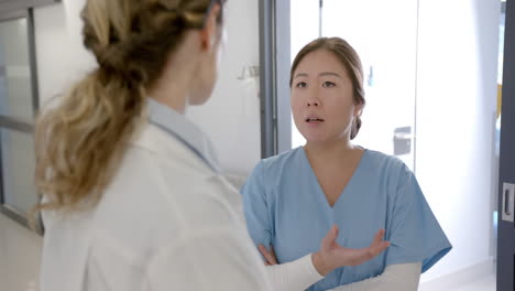 Serious-diverse-female-doctors-discussing-in-hospital-corridor,-slow-motion
