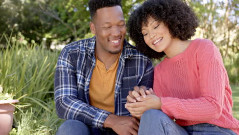 Portrait-of-happy-african-american-couple-crouching-in-garden-at-home,-slow-motion