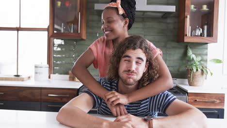 Diverse-couple:-a-young-African-American-woman-embraces-a-young-Caucasian-man-in-a-home-kitchen
