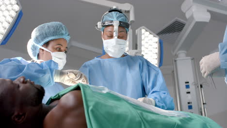 Diverse-female-surgeons-operating-on-african-american-patient-in-operating-theatre,-slow-motion