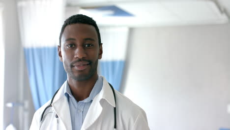 Portrait-of-african-american-male-doctor-smiling-in-hospital-ward,-copy-space,-slow-motion