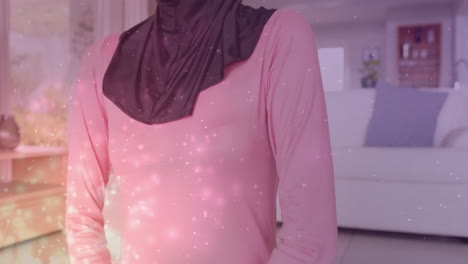 Animation-of-light-spots-over-biracial-woman-in-hijab-practicing-yoga