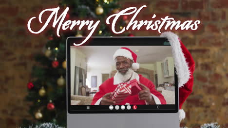 Animation-Des-Textes-„Frohe-Weihnachten“-über-Dem-Weihnachtsmann-Auf-Dem-Laptop-Bildschirm-Und-Weihnachtsdekorationen