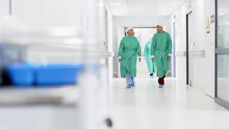 Diversos-Cirujanos-Masculinos-Y-Femeninos-Con-Batas-Quirúrgicas-Caminando-Por-El-Pasillo-Del-Hospital,-En-Cámara-Lenta