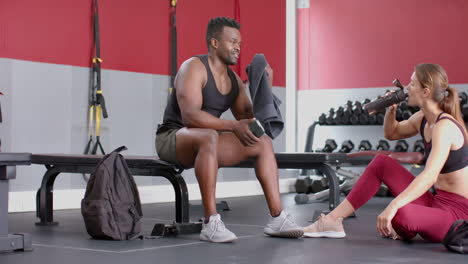Fit-African-American-man-and-young-Caucasian-woman-rest-at-the-gym