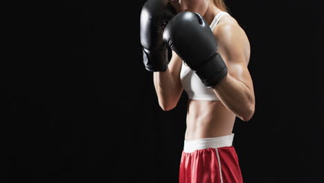 Young-Caucasian-woman-boxer-in-boxing-gear,-with-copy-space-on-a-black-background