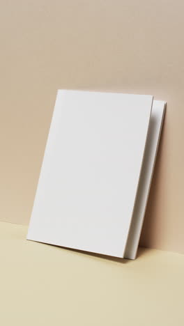 Vertical-video-of-book-with-white-blank-pages-and-copy-space-on-yellow-background