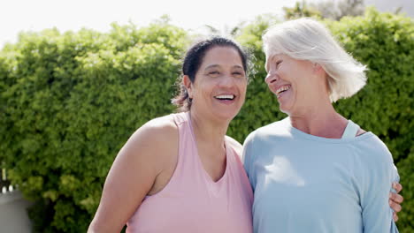 Two-happy-diverse-senior-women-embracing-and-smiling-in-sunny-garden,-slow-motion