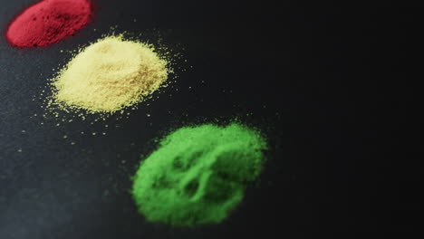 Video-of-red,-yellow-and-green-powders-with-copy-space-on-black-background