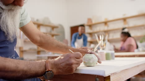 Hands-of-biracial-male-potter-glazing-clay-jug-in-pottery-studio,-slow-motion