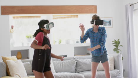 Happy-diverse-teenage-female-friends-playing-and-wearing-vr-headsets-at-home,-slow-motion
