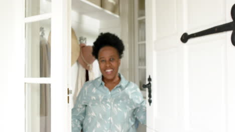 Happy-african-american-senior-woman-standing-at-door-of-house-and-smiling,-slow-motion