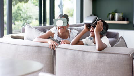 Happy-african-american-brother-and-sister-in-vr-headsets-on-sofa,-copy-space,-slow-motion