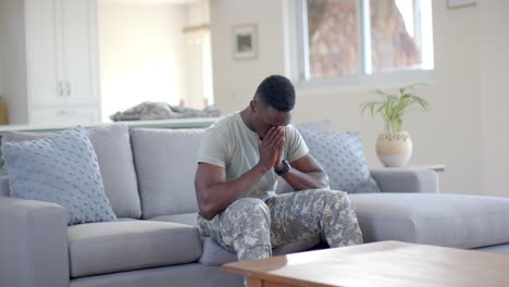 Besorgter-Afroamerikanischer-Soldat,-Der-Im-Sonnigen-Wohnzimmer-Die-Hand-Auf-Den-Kopf-Legt,-Zeitlupe