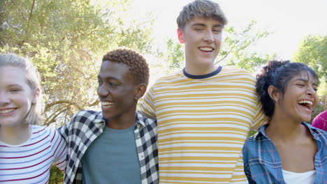 Portrait-of-happy-diverse-group-of-teenage-friends-embracing-in-sunny-park,-slow-motion