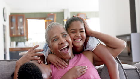 Happy-african-american-grandchildren-embracing-grandmother-on-sofa,-slow-motion