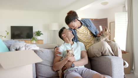 Portrait-of-happy-diverse-gay-male-couple-with-pet-dogs-in-living-room,-copy-space,-slow-motion
