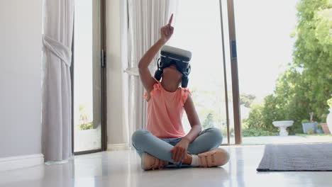 Happy-biracial-girl-wearing-vr-headset-using-virtual-interface-at-home,-slow-motion