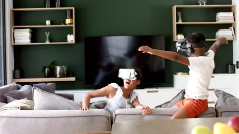Happy-african-american-brother-and-sister-in-vr-headsets-on-sofa,-copy-space,-slow-motion