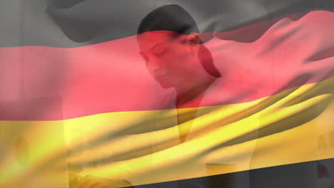 Animation-of-flag-of-germany-over-smiling-biracial-businesswoman-using-laptop