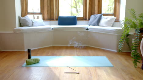 Incense-sticks-with-smoke-trails-on-floor-over-yoga-mat-at-home