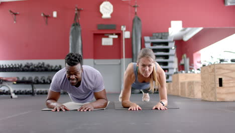 Fit-diverse-couple-doing-planks-at-the-gym