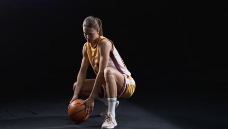 Young-Caucasian-woman-poses-in-basketball-attire-on-a-black-background