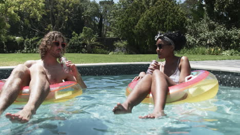 Diverse-couple,-a-Caucasian-man-and-an-African-American-woman,-enjoy-pool-time