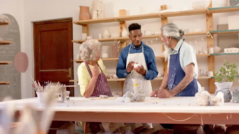 Happy-diverse-group-of-potters-discussing-about-work-in-pottery-studio