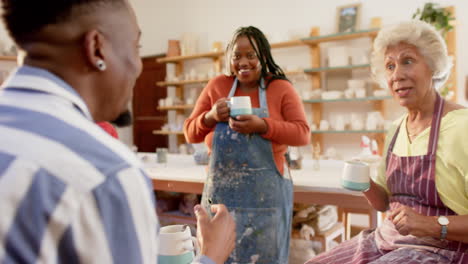 Happy-diverse-group-of-potters-discussing-and-laughing-in-pottery-studio