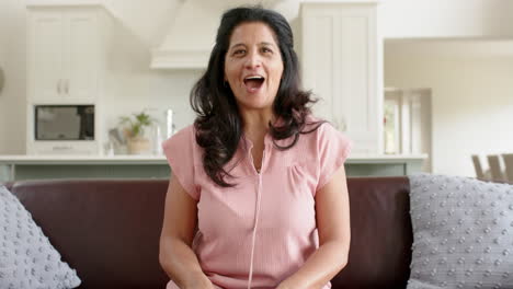 Happy-biracial-senior-woman-having-video-call-and-smiling-in-sunny-living-room,-slow-motion