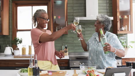 Glückliche-ältere-Afroamerikanische-Freundinnen,-Die-Beim-Kochen-Mit-Wein-Anstoßen,-Zeitlupe