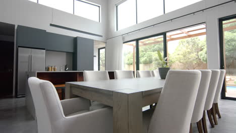 Interior-of-bright-open-plan-dining-room-and-kitchen-with-doors-to-garden,-copy-space,-slow-motion