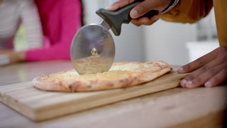 Diverse-teenage-friends-cooking-and-cutting-pizza-in-kitchen,-slow-motion