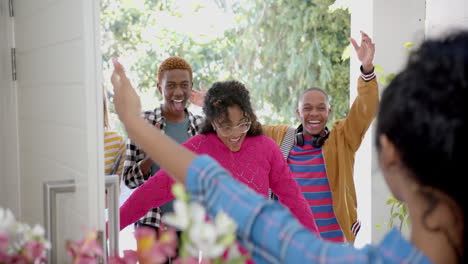Happy-diverse-group-of-teenage-friends-greeting-and-embracing-at-door-at-home,-slow-motion
