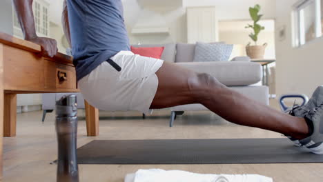 Focused-african-american-man-doing-push-ups-on-table-in-sunny-living-room,-slow-motion
