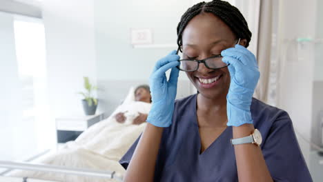 Portrait-of-happy-african-american-female-doctor-with-eyeglasses-in-hospital-room,-slow-motion