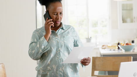 Afroamerikanische-Seniorin-Erledigt-Papierkram-Und-Benutzt-Smartphone-In-Sonnigem-Zimmer,-Zeitlupe