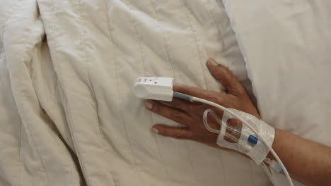 Hand-of-african-american-senior-female-patient-sleeping-in-bed-in-hospital-room,-slow-motion