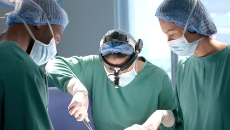 Diversos-Cirujanos-Masculinos-Y-Femeninos-Que-Utilizan-Herramientas-Quirúrgicas-Y-Faros-Durante-La-Cirugía,-Cámara-Lenta