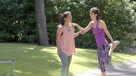 Happy-asian-female-friends-stretching-in-garden-on-sunny-day,-slow-motion