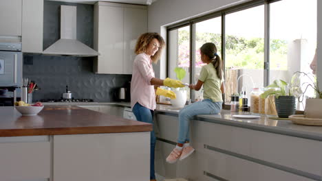Biracial-mother-and-daughter-washing-and-drying-dishes-in-kitchen,-copy-space,-slow-motion